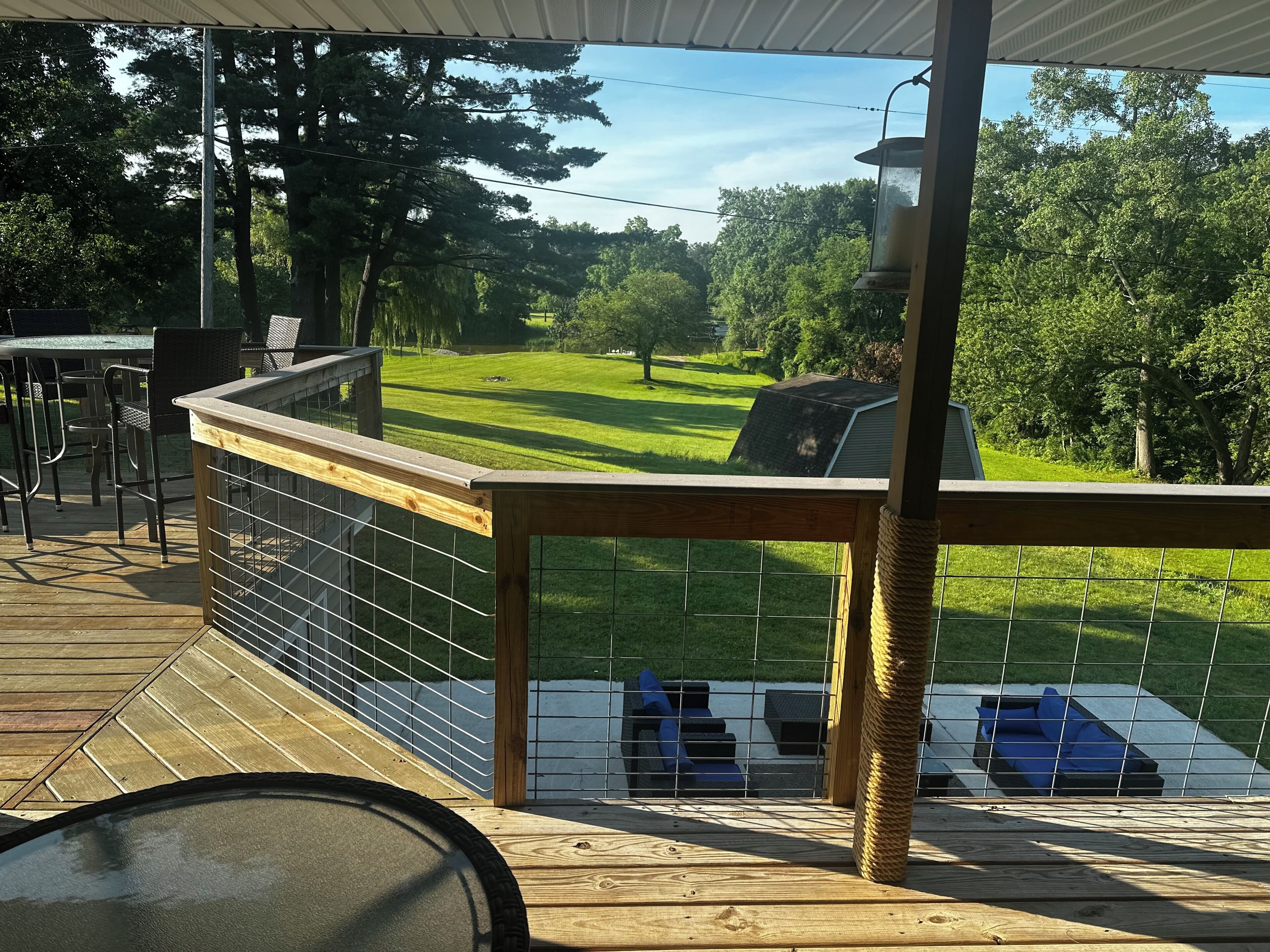 A covered deck with a view of a grassy yard and a solar panel.