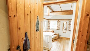 Una puerta de madera con picaporte y cerradura, que da a un cuarto con piso de madera, un armario blanco y una ventana con cortinas.