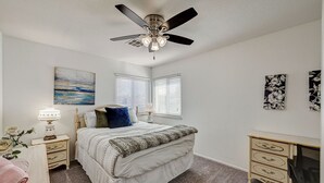A bedroom with a bed, a nightstand, a dresser, a ceiling fan, and two windows with blinds. - Spacious 4 bedroom with 7 beds! (Las Vegas)