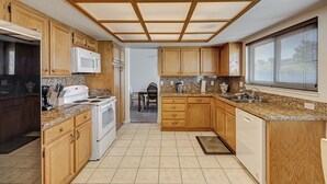 A compact kitchen with wooden cabinets, a microwave, stove, and granite countertops. - Spacious 4 bedroom with 7 beds! (Las Vegas)