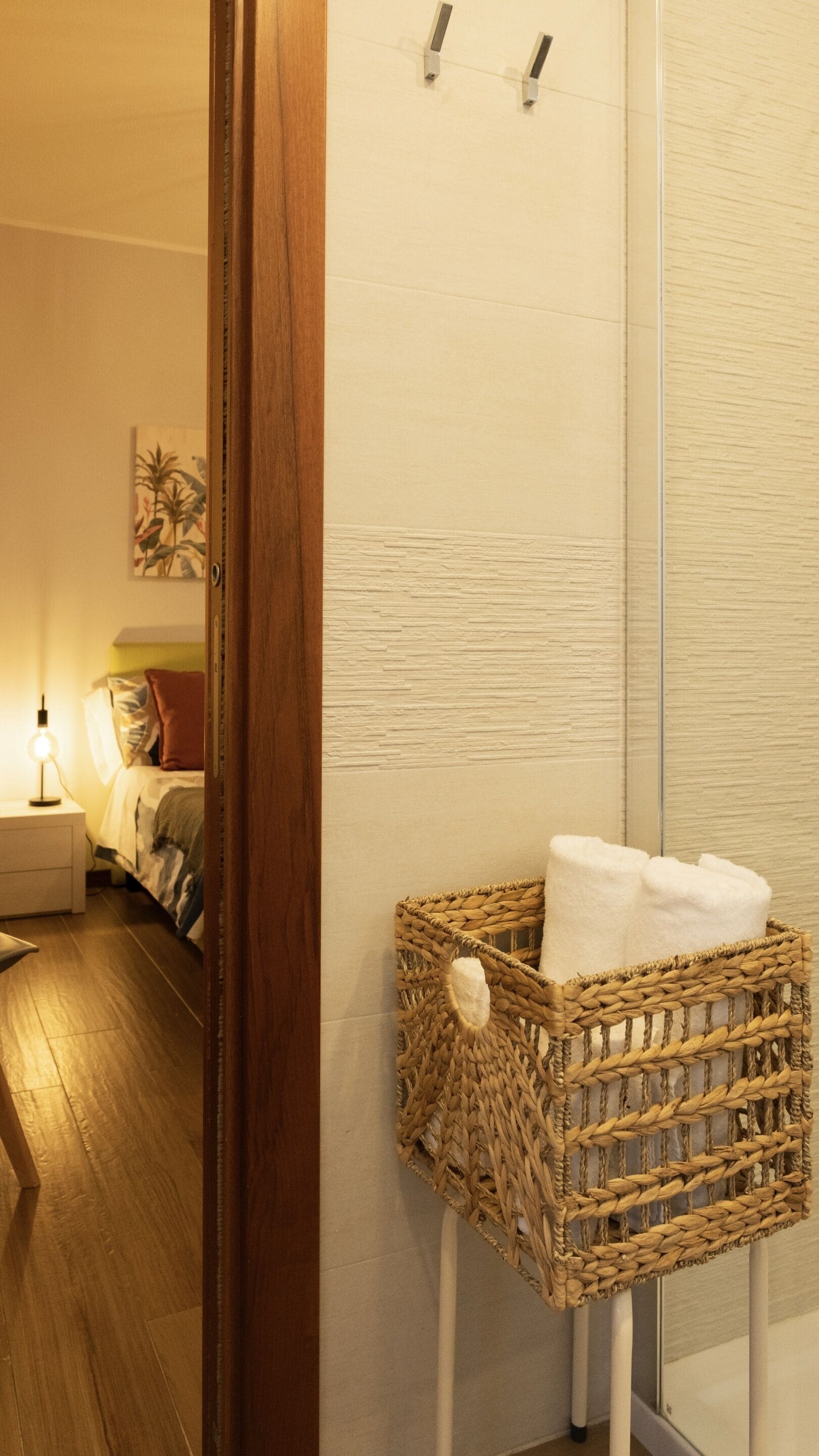 A wicker basket with towels on a white stand in a bathroom.