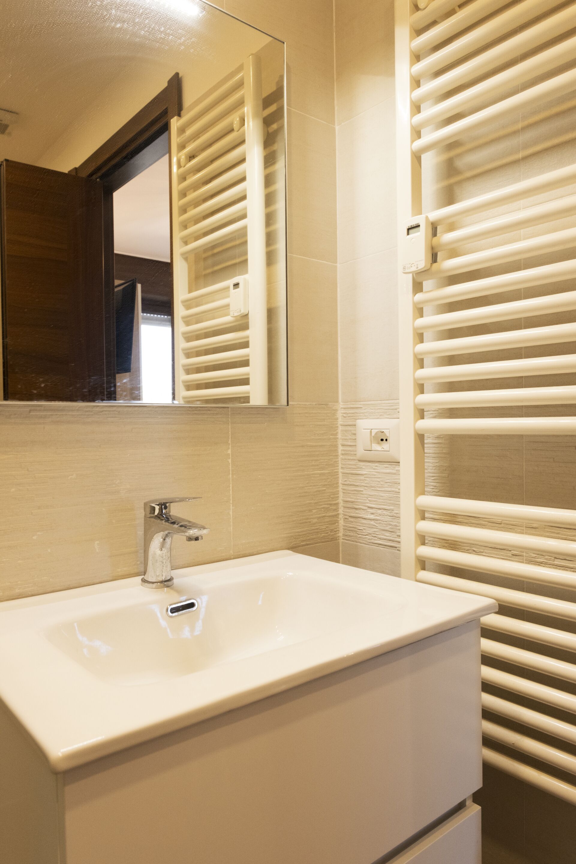 Une salle de bain avec un lavabo blanc, un miroir et un porte-serviettes.