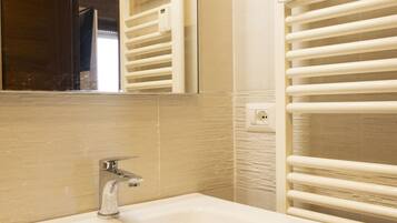Une salle de bain avec un lavabo blanc, un miroir et un porte-serviettes.
