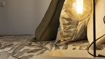 Een bed met een bedspread met patroon, een kussen en een lamp met een glazen kap.
