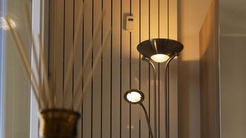 Un interno moderno con una lampada da terra alta e slanciata e un vaso decorativo su un tavolo.