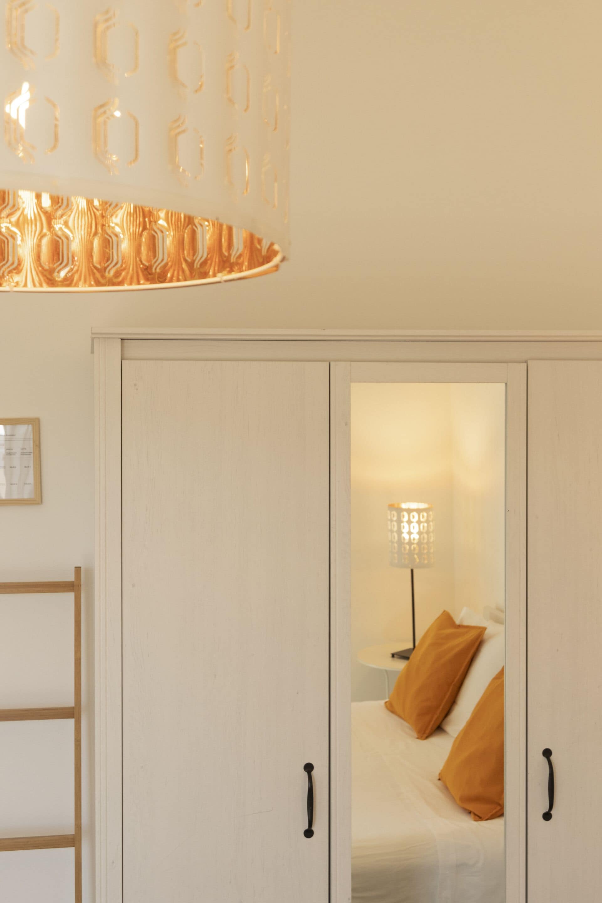 A room with a bed, a nightstand, a lamp, and a wardrobe.