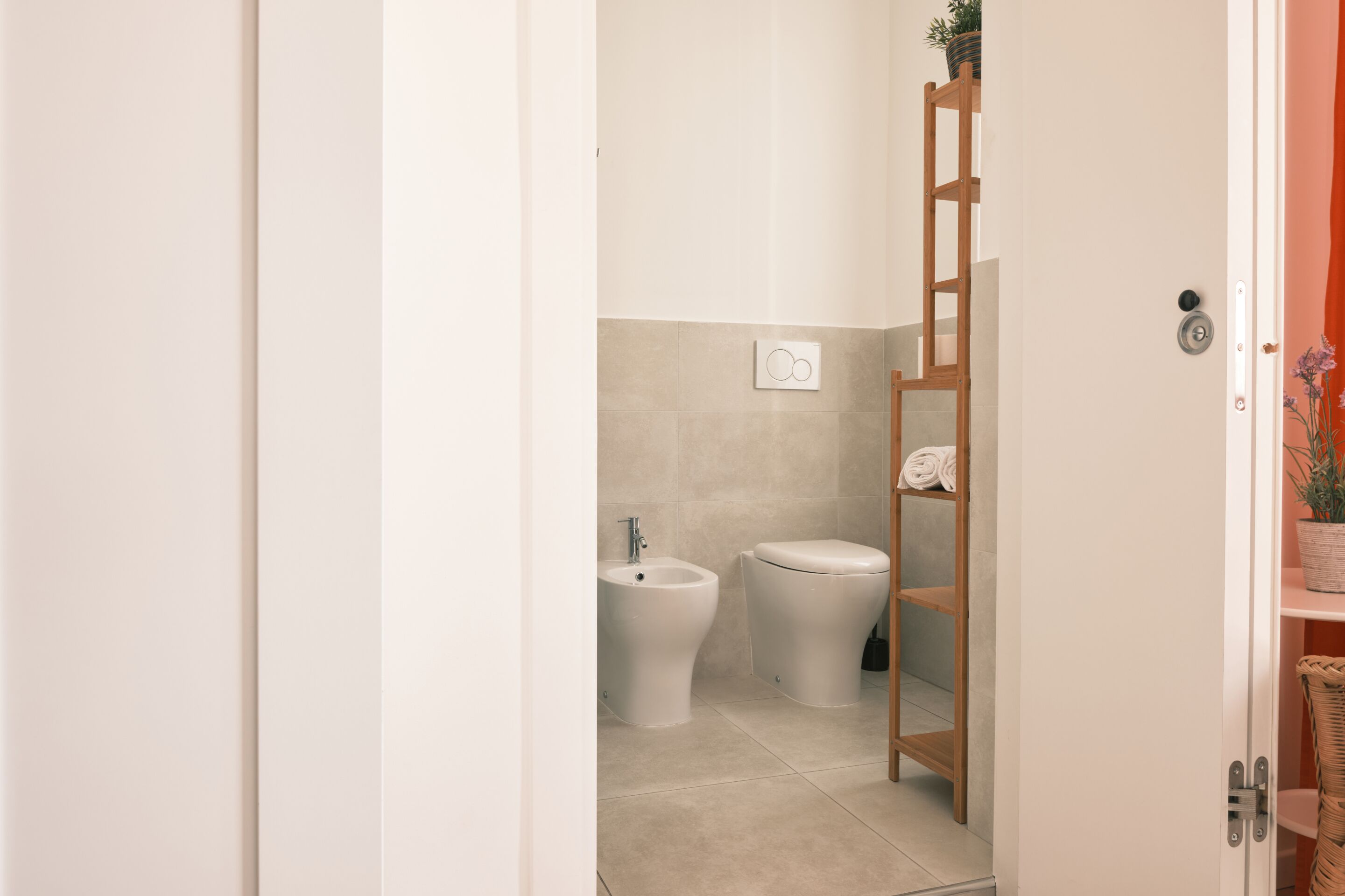 A bathroom with a bidet, toilet, and a wooden ladder.