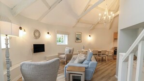 A modern living room with a sofa, armchair, and a dining table. - Round Barn (Ilfracombe)