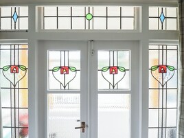 Una puerta blanca con cuatro vidrieras de motivos florales.
