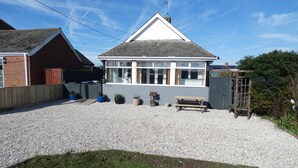 A two-story house with a white facade, a pitched roof, and a gravel driveway. - Orby Cottage (Skegness)