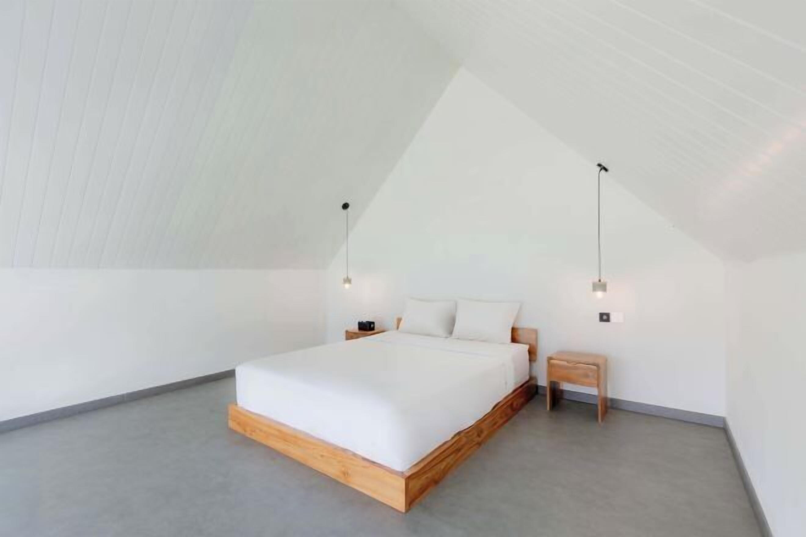 Un dormitorio moderno con un cabecero de madera, una mesita de noche y dos luces fijadas a la pared.