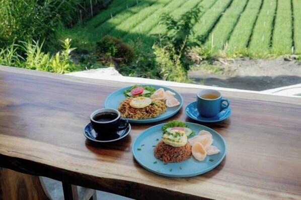 A table with two plates of food, a cup of coffee, and a small bowl of soup. - Faro Cabin Kintamani (Bali)