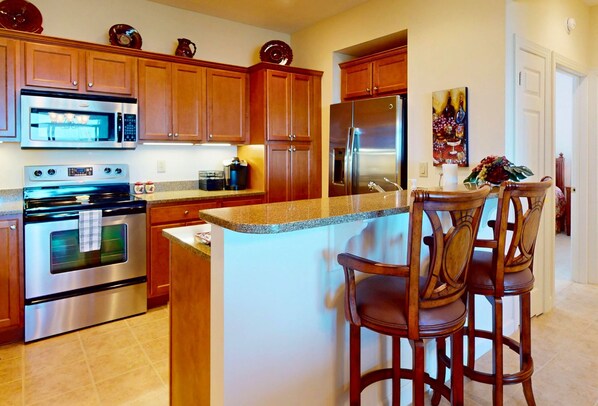 A kitchen with wooden cabinets, stainless steel appliances, and a granite countertop. - Reserve II 7C • Peaks & Pines Getaway (Sugar Mountain)