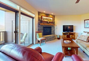 A spacious living room with a stone fireplace, a television, and a sofa.