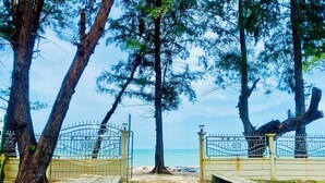 A pathway leading to a beach through a gate, surrounded by trees and a clear sky. - Leelavadee Villa Sea Views (Tha Sala)