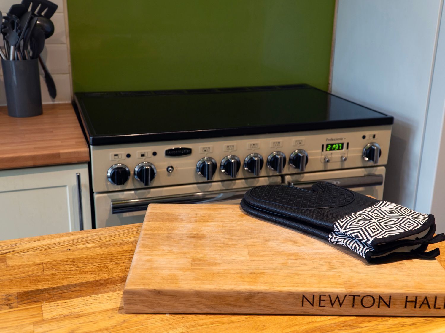 A kitchen with a stove, a cutting board, and a black and white patterned bag on the counter.