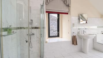 Une salle de bain moderne avec une douche à parois de verre, une grande fenêtre offrant une belle vue, un lavabo et une baignoire.