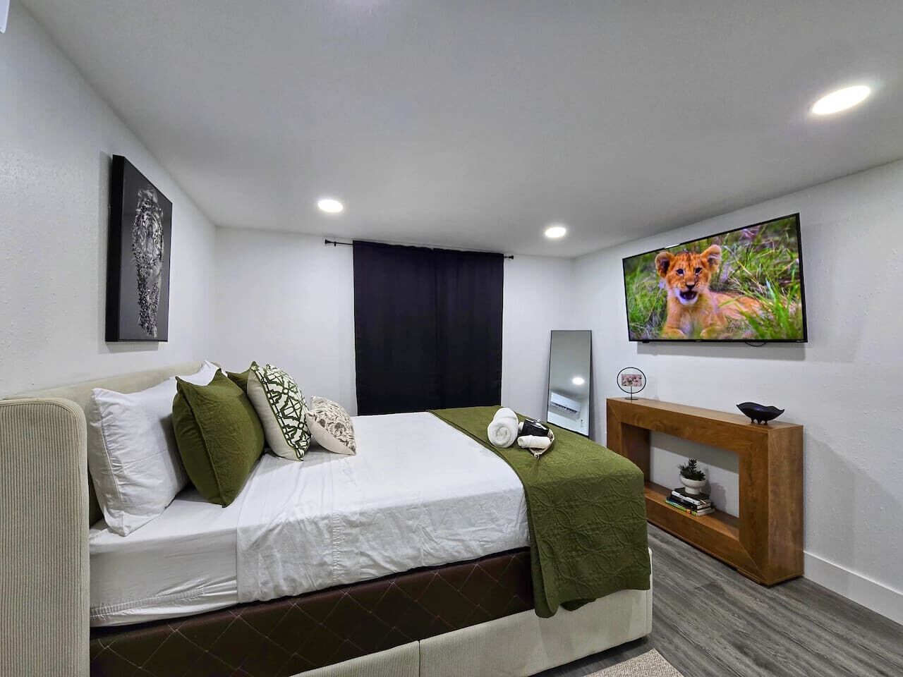 Quarto de hotel com cama, televisão, mesa de apoio e um quadro na parede.