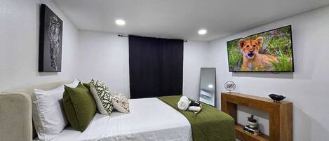Quarto de hotel com cama, televisão, mesa de apoio e um quadro na parede.