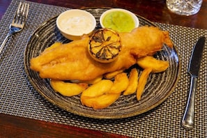 A plate of fish and chips with two dipping sauces and a glass of water. - Bruntsfield Hotel, WorldHotels Elite (Edinburgh)
