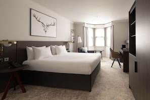 A hotel room with a large bed, a desk, a chair, a television, and a window with curtains. - Bruntsfield Hotel, WorldHotels Elite (Edinburgh)