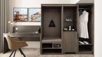 Een moderne hotelkamer met een bureau, een bankje, een garderobe en een schoenenrek.