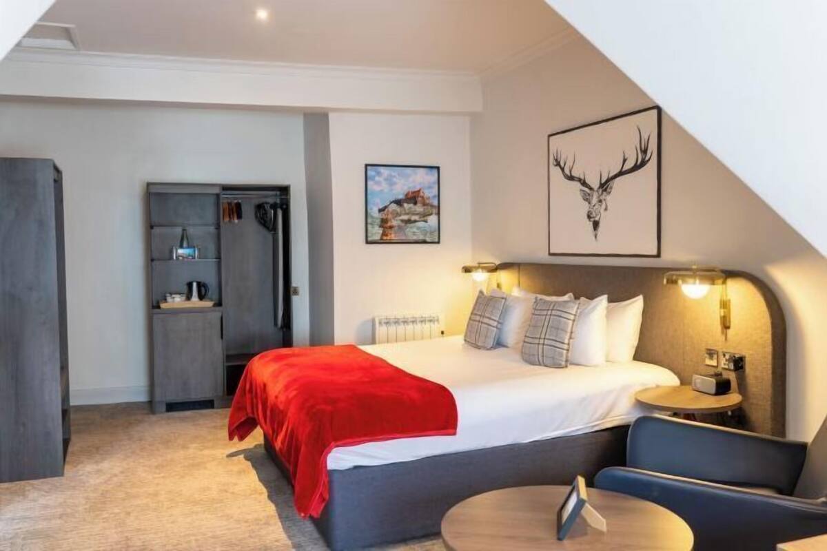 A bedroom with a bed, bedside table, and a chair.