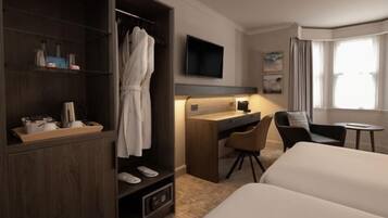 Een hotelkamer met een bed, een bureau, een stoel, een televisie, een kledingkast en een raam.