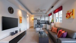 A modern living room with a flat-screen TV, a sofa, and a coffee table. - Orchid Paradise Homes OPV 213 (Hua Hin)