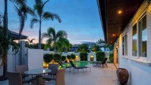 An outdoor patio with a round table and chairs, a small pool, and palm trees. - Orchid Paradise Homes OPV 213 (Hua Hin)