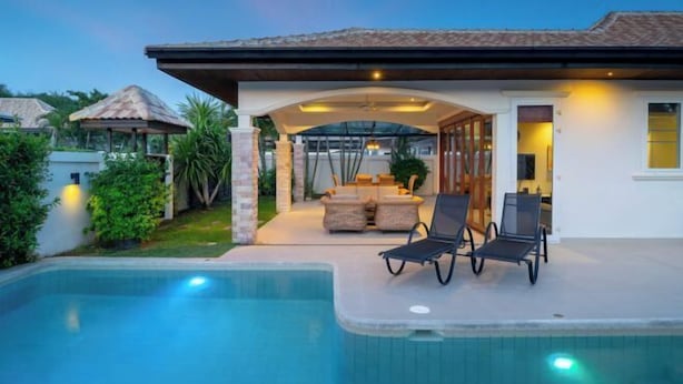 A modern house with a swimming pool, outdoor seating, and a covered patio area. - Orchid Paradise Homes OPV 213 (Hua Hin)