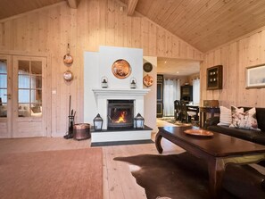 A cozy living room with a fireplace, wooden walls, and a leather sofa.
