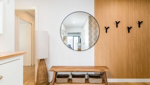 A modern interior with a round mirror, a wooden table with baskets, and a wooden wall with letters. - Miraflores Modern Apt w/ Balcony by LovelyStay (Algés)