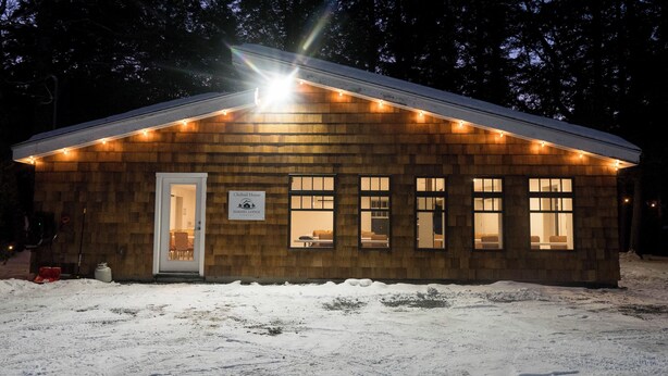 Une cabane en bois avec une enseigne indiquant « Chabad House Hakhel Lodge Vermont » et de nombreuses fenêtres.