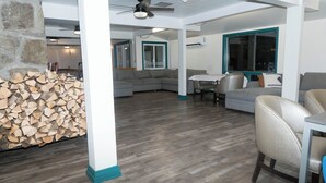 Un vaste espace de vie agrémenté d’un mur en pierre, d’un grand canapé d’angle gris, d’une table à manger et d’un ventilateur de plafond.