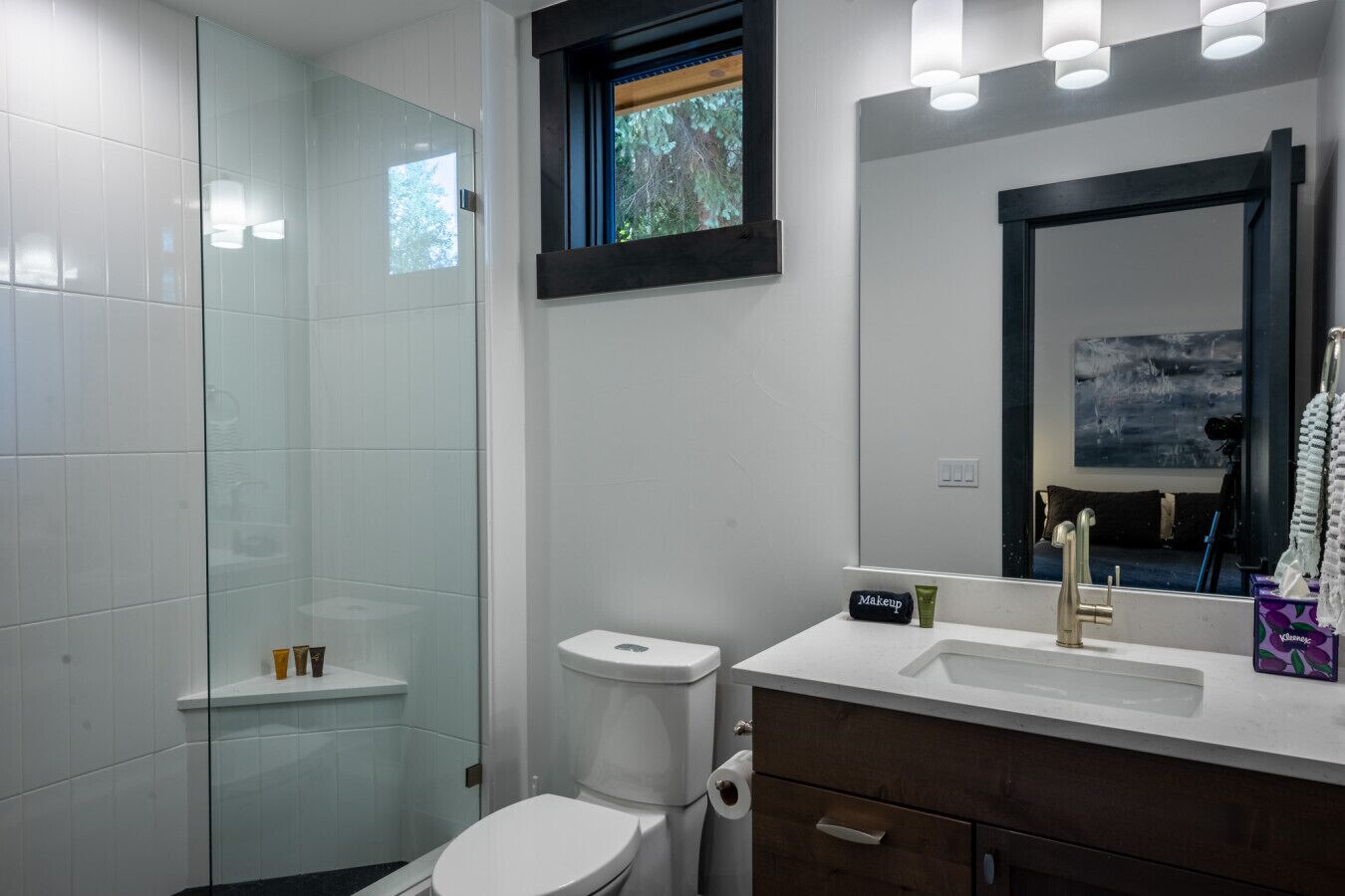 Un bagno moderno con cabina doccia in vetro, un WC bianco, un mobile lavabo e un grande specchio.