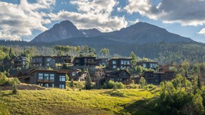 Un conjunto de casas modernas con ventanas amplias, frente a un paisaje de montañas y cielo despejado.