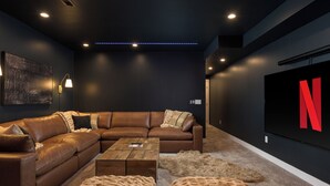 A modern living room with a sectional sofa, a coffee table, and a large flat-screen TV with a Netflix logo. - Brand New Luxury Marquee Inn (Denver)