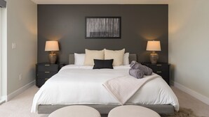A modern bedroom with a large bed, two bedside tables with lamps, a framed artwork on the wall, and a view of the outdoors. - Brand New Luxury Marquee Inn (Denver)
