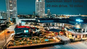 A hotel with a spacious outdoor area featuring a pool and seating, surrounded by high-rise buildings. - Left Apt.2BR| 7` TPA Airport| AC| Pkng| Wine| HSIA (Tampa)