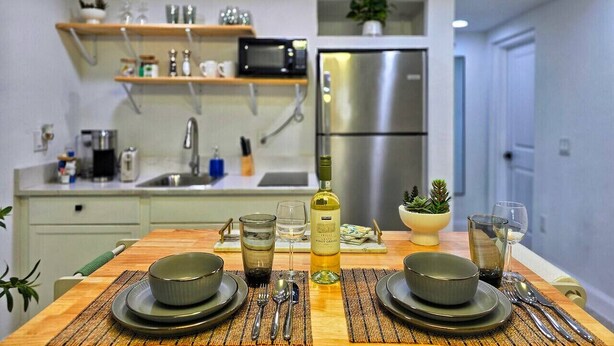 A modern kitchen with a dining table set for two, a microwave, a refrigerator, and a potted plant on the counter. - Left Apt.2BR| 7` TPA Airport| AC| Pkng| Wine| HSIA (Tampa)