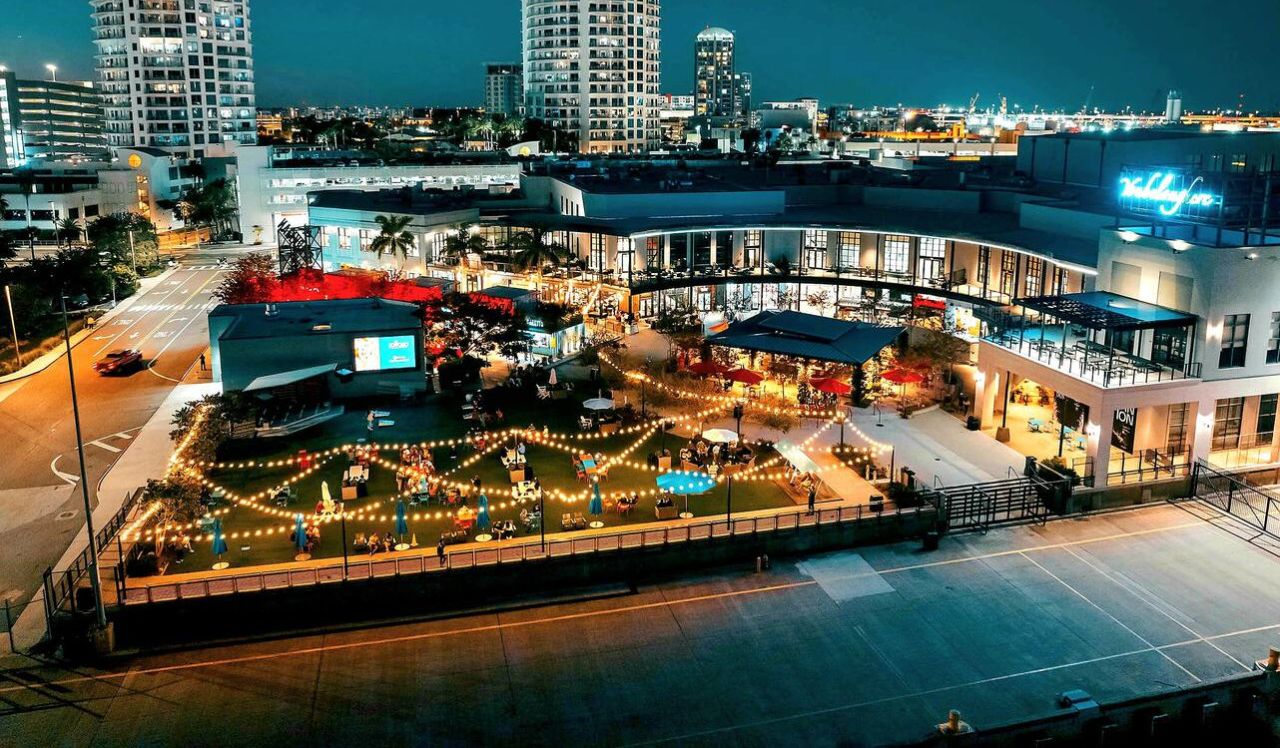 A hotel with a spacious outdoor area featuring a pool and seating, surrounded by high-rise buildings.