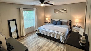 A bedroom with a bed, bedside tables, a desk, and a ceiling fan.