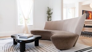 Ein modernes Wohnzimmer mit einem beigen Sofa, einem schwarzen Couchtisch und einem Streifen Teppich.