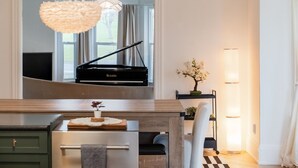 Ein modernes Wohnzimmer mit einem Flügel, einer Kristallleuchter und einer minimalistischen Einrichtung.