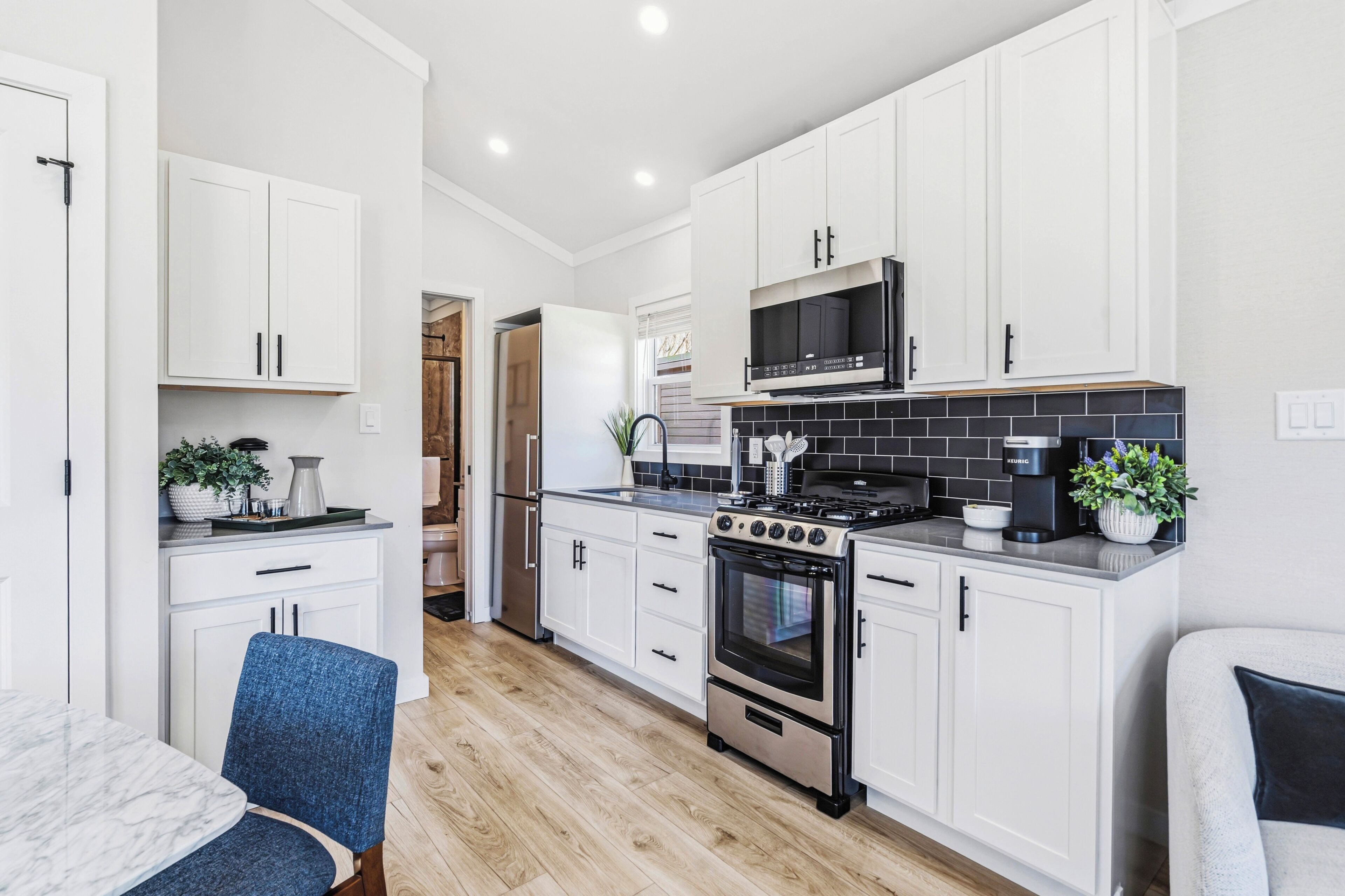 Una cocina moderna con armarios blancos, estufa de acero inoxidable y un microondas.