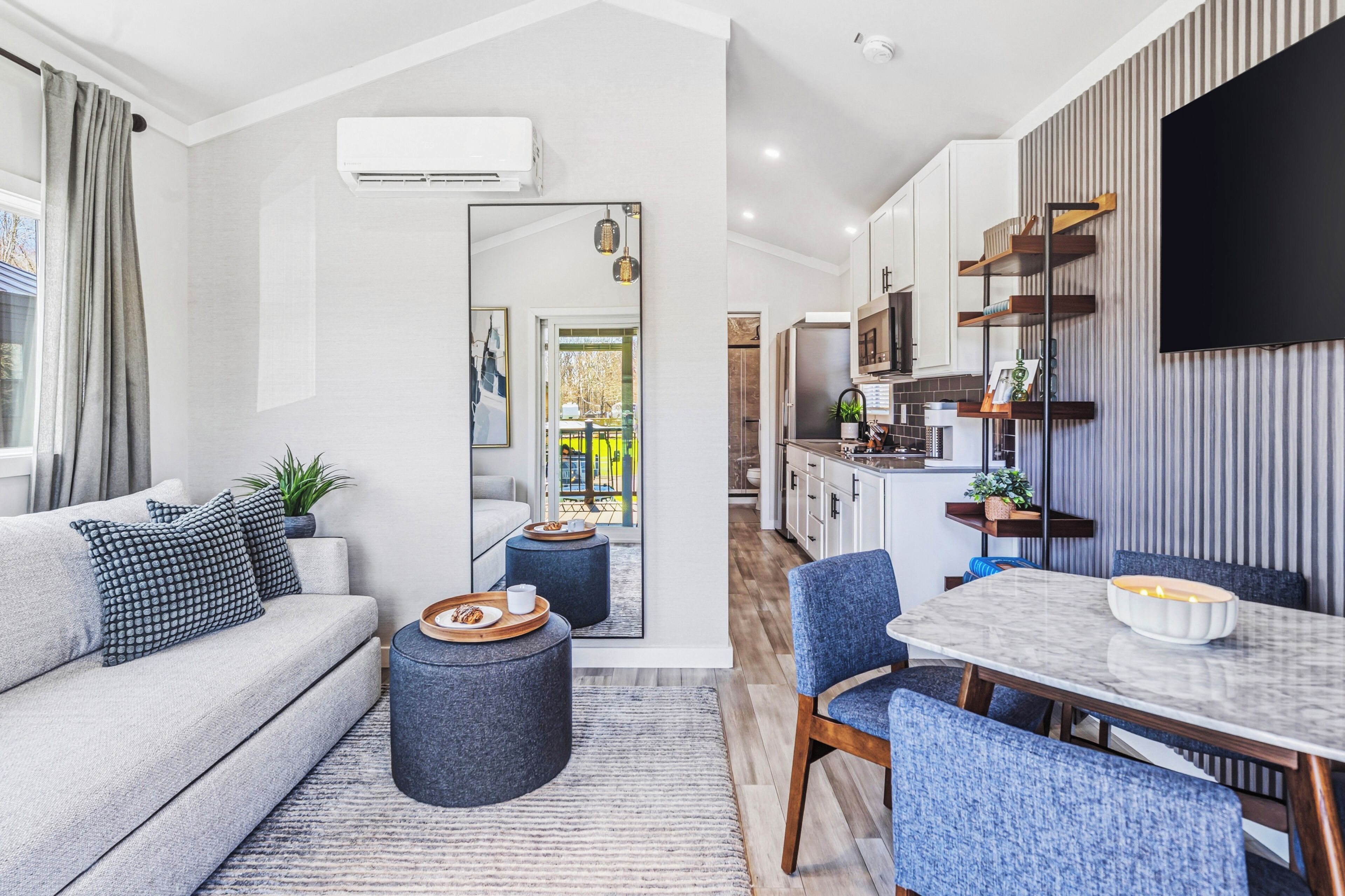 A modern living room with a sofa, coffee table, and dining area with chairs and a table.