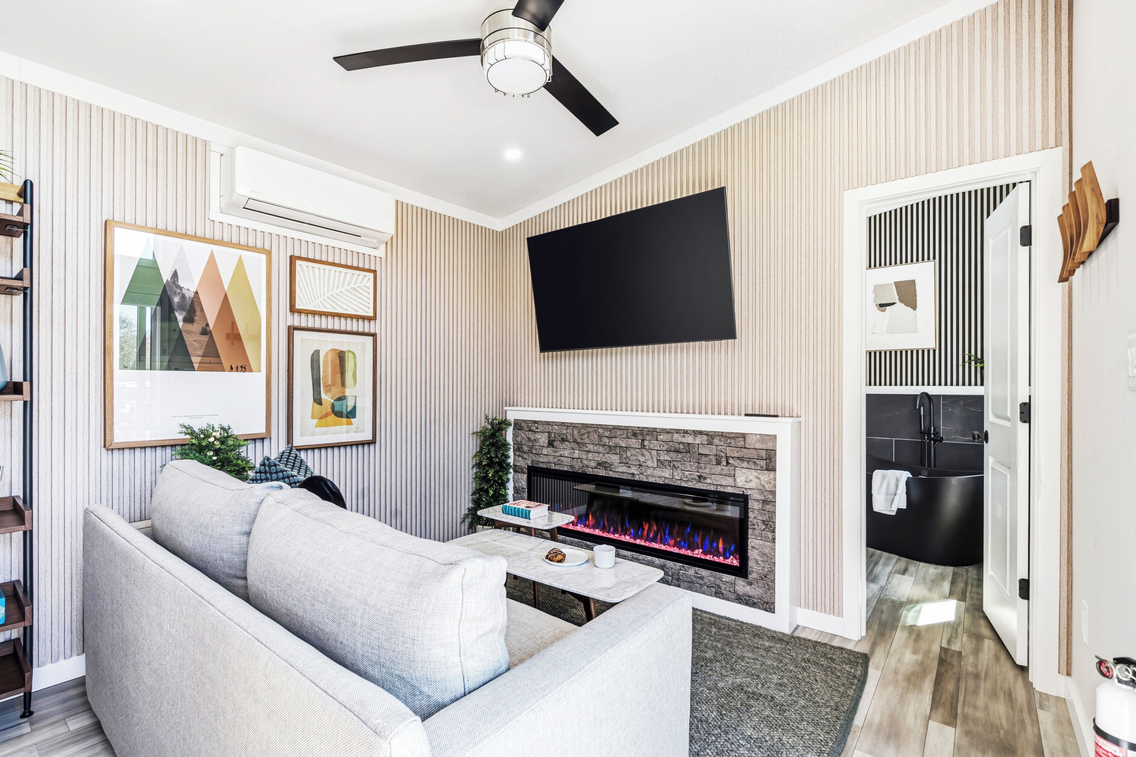 A living room with a sofa, a flat-screen TV, a fireplace, and a ceiling fan.