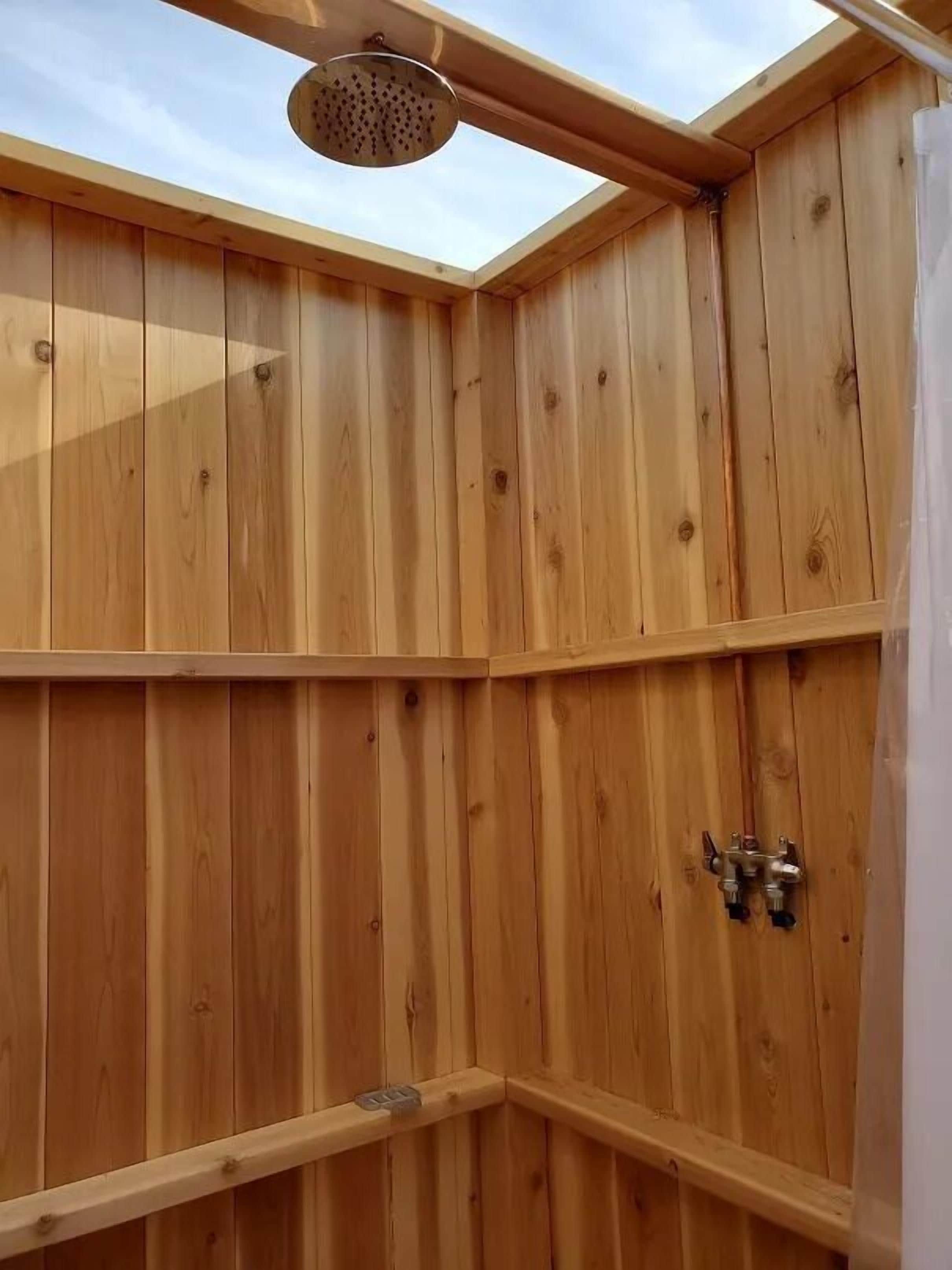 A wooden sauna with a skylight, a showerhead, and a water control valve.