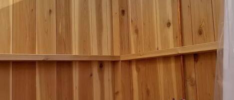 A wooden sauna with a skylight, a showerhead, and a water control valve.